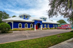 The exterior of the Dennis Hernandez Injury Attorneys office in St. Petersburg, Florida, featuring its bright blue façade with white trim and red entrance.
