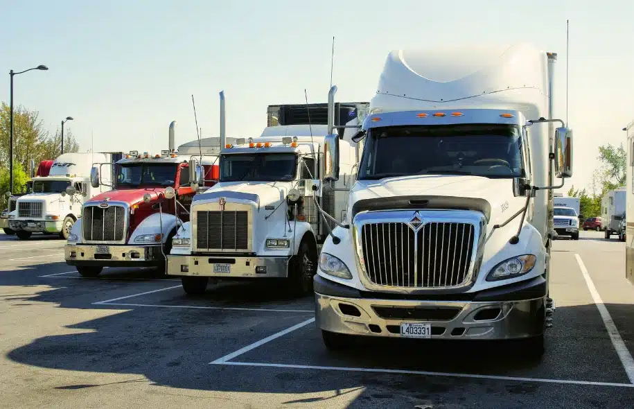 Commercial semi trucks parked together, representing trucking regulations, driver responsibilities, and potential legal penalties for violations.