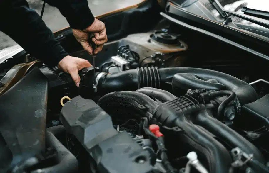 Technician working under a vehicle hood, representing black box data recovery and electronic evidence used in accident investigations.