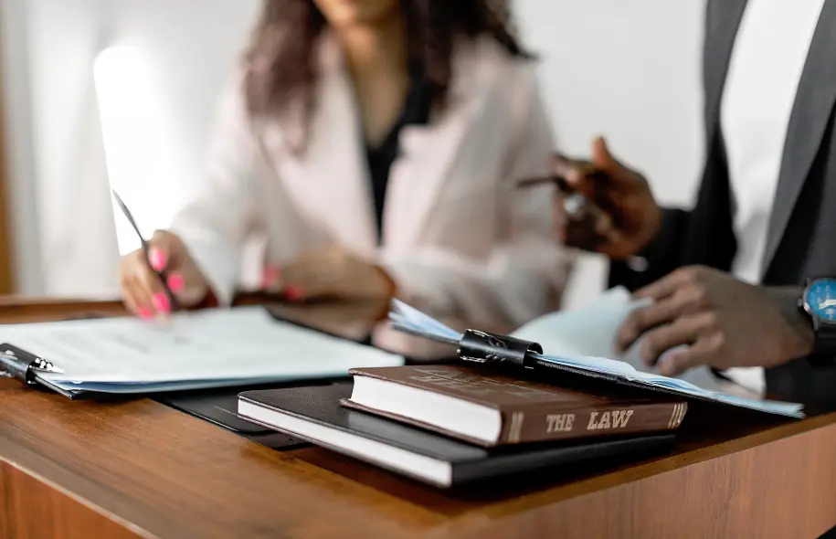 Legal professionals reviewing documents with a law book, representing interrogatories in a personal injury motor vehicle lawsuit.
