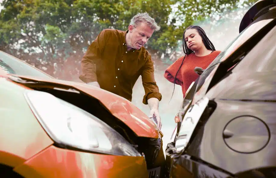 Two people inspecting vehicle damage after a car accident collision.