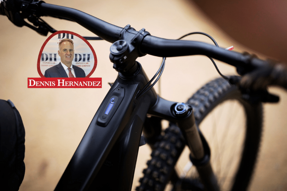 Close-up of an electric bicycle handlebar and control panel with Dennis Hernandez Injury Attorneys logo overlay.