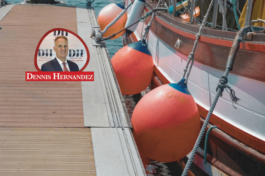 Boat dock with red fenders tied to a wooden pier, used for collision protection, branded with Dennis Hernandez logo.