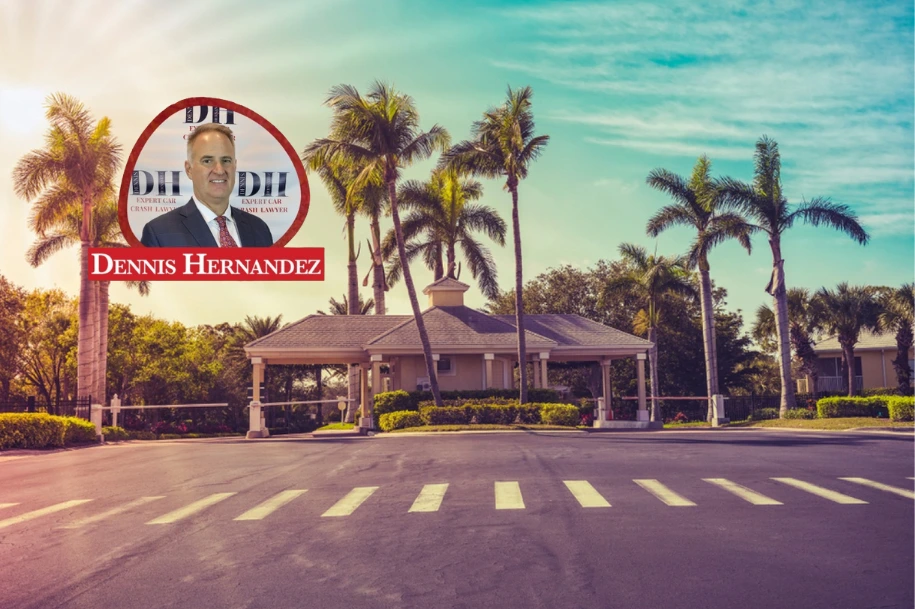 Gated residential community entrance surrounded by palm trees under a bright Florida sky, with Dennis Hernandez Injury Attorneys logo overlayed.