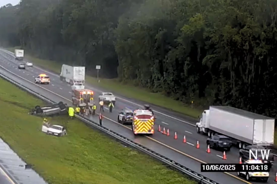 Emergency responders assisting at a highway rollover crash with overturned vehicle and blocked lanes.