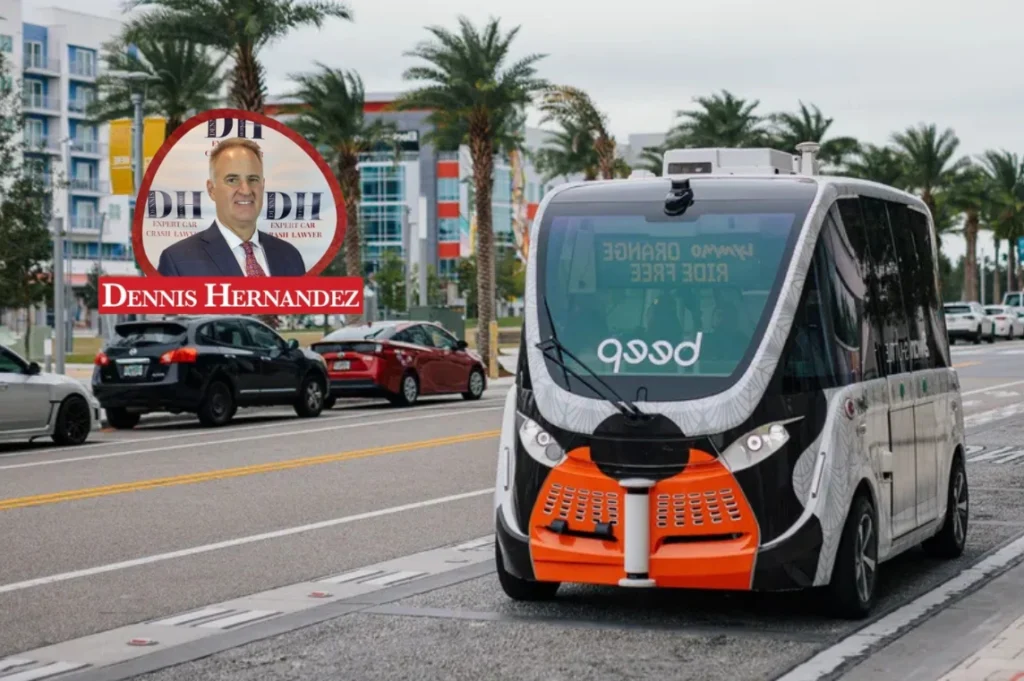 Autonomous shuttle bus driving in an urban area with palm trees and traffic, featuring the Dennis Hernandez Injury Attorneys logo overlay.