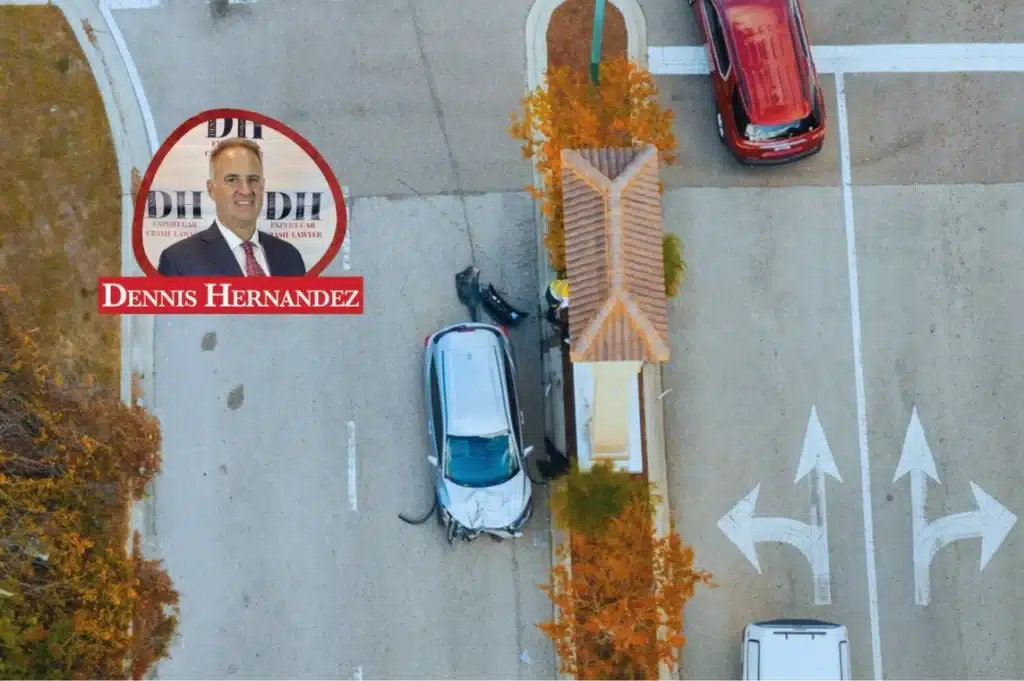 Aerial view of a car that crashed into a gated community entrance structure, with the Dennis Hernandez Injury Attorneys logo overlay.