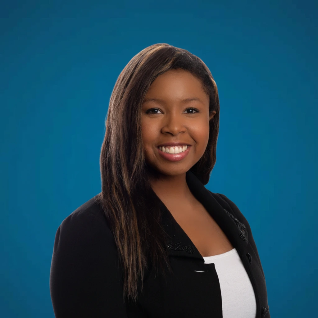Portrait of Attorney Alleah Thornhill, smiling confidently in a professional black blazer against a blue background.