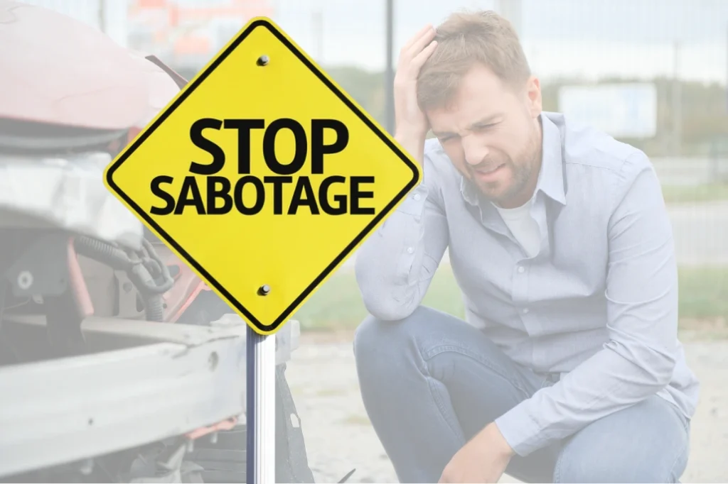 Yellow road sign reading “Stop Sabotage” over a distressed man near a damaged vehicle.