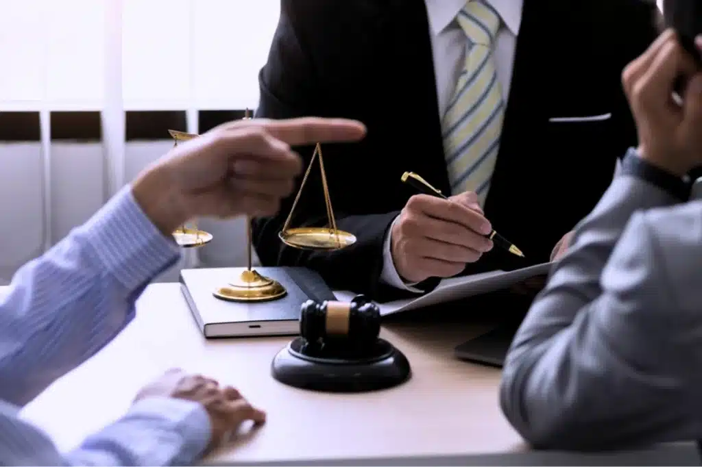 Attorney meeting with clients at a desk, with scales of justice and a gavel visible during a legal consultation.