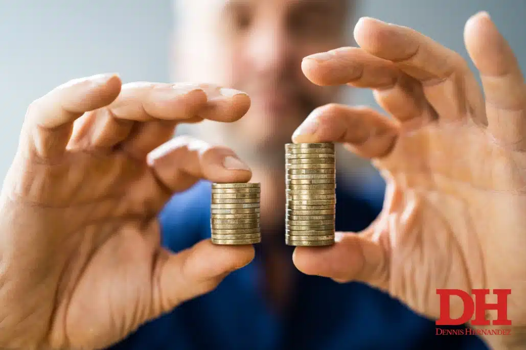 Person holding two stacks of coins of different heights, comparing financial value or compensation.