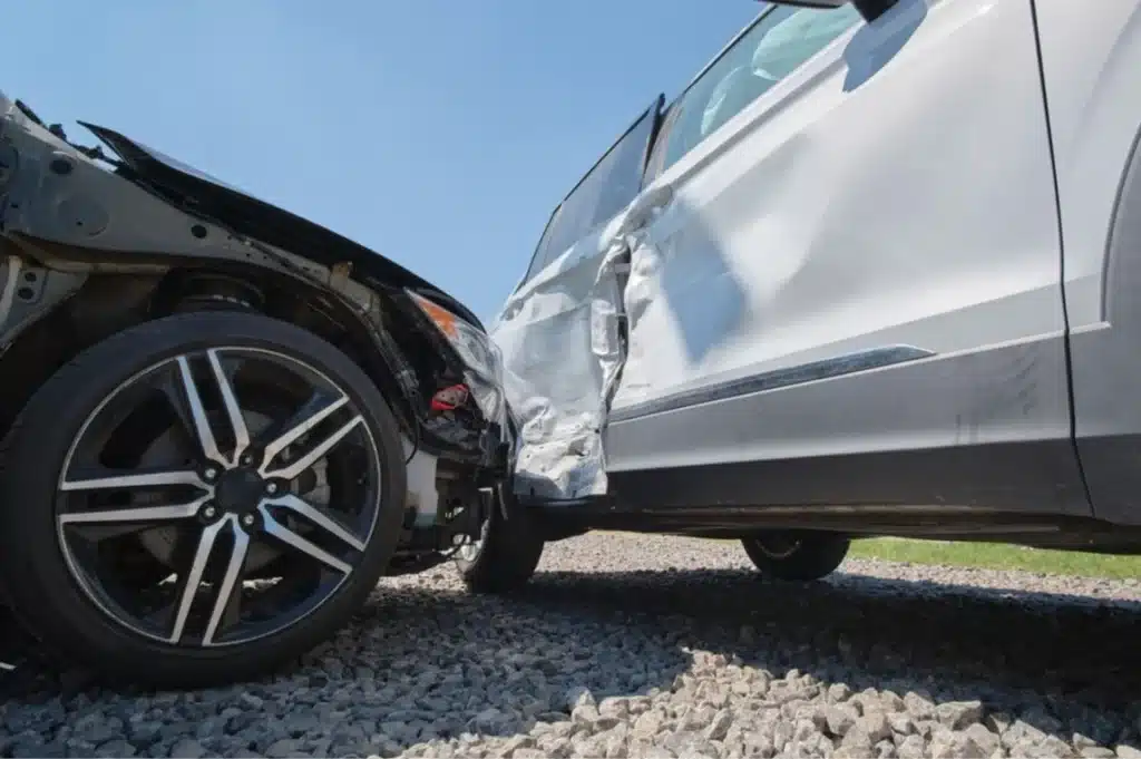 Close-up of a car crash showing one vehicle’s front end pressed into the side of another vehicle with visible door damage.