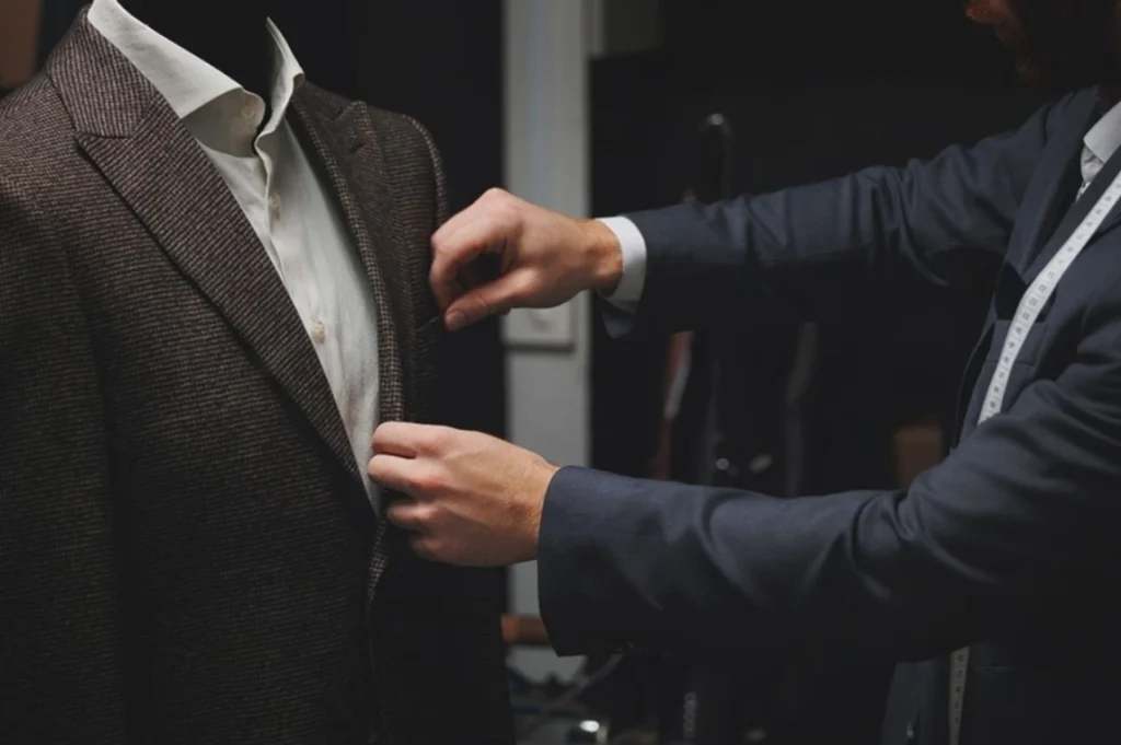 Tailor adjusting the lapel of a suit jacket on a mannequin in a clothing shop.