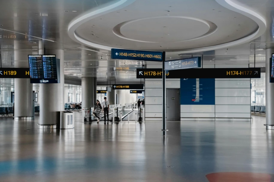 Modern airport terminal concourse with gate direction signs and a few travelers, representing travel and transportation injury risks handled by Dennis Hernandez Injury Attorneys.