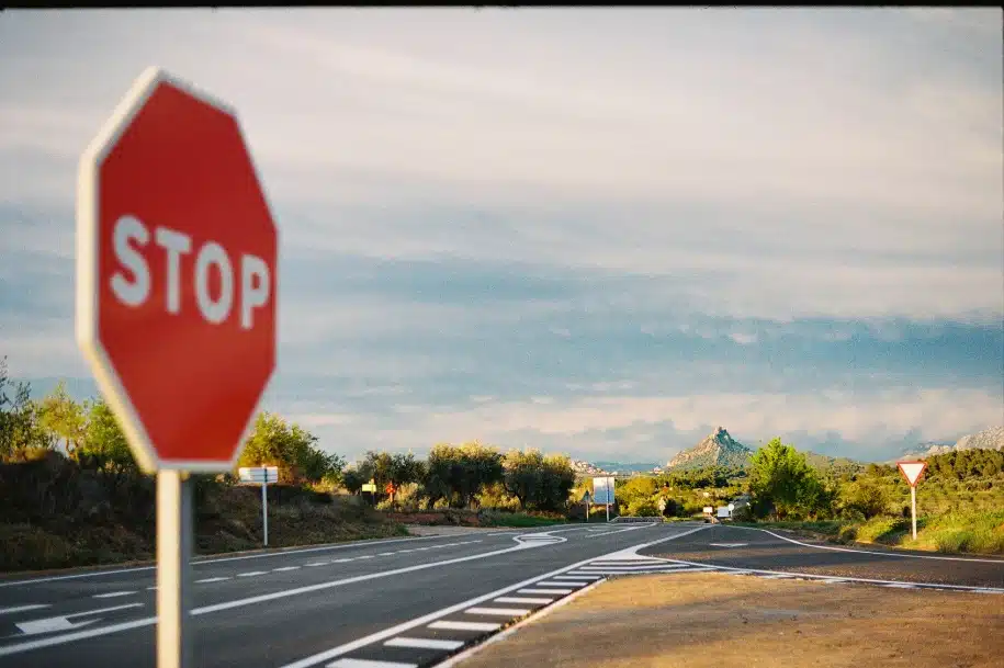 Stop sign at a rural roadway intersection with open lanes and distant hills in the background.
