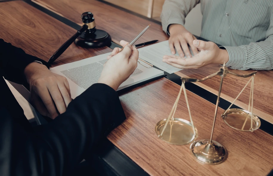 Personal injury attorney reviewing legal documents with a client at a desk, with scales of justice and a gavel visible.