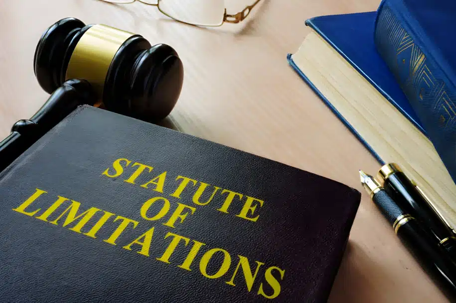 Law book labeled statute of limitations next to a gavel and legal documents on a desk.