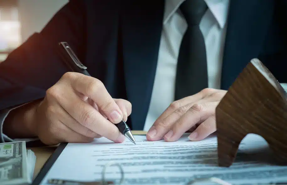 Close-up of a person in a suit signing legal documents related to an injury claim.