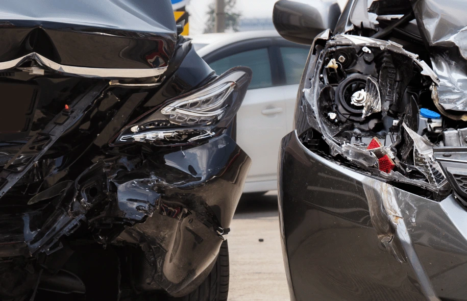Close-up of two cars with significant front-end damage after a crash.
