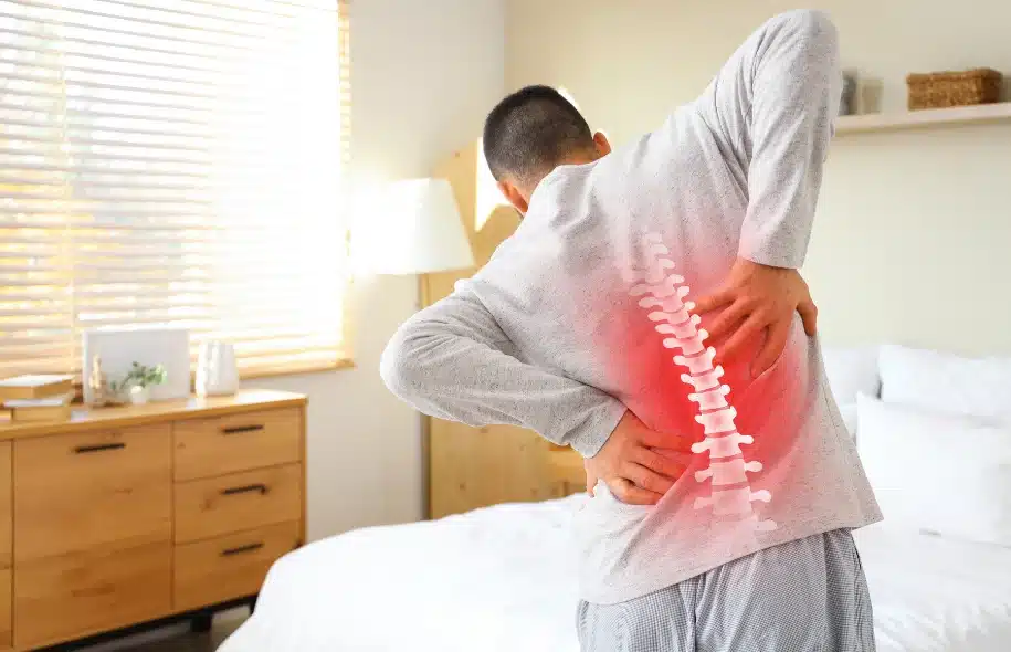 Person holding lower back with highlighted spine indicating pain or injury.