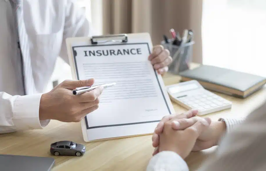 Insurance representative explaining policy documents to a client after a car accident.