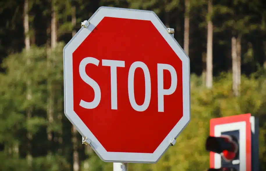 Red stop sign at a roadway intersection highlighting traffic control measures and driver responsibility to stop before proceeding.