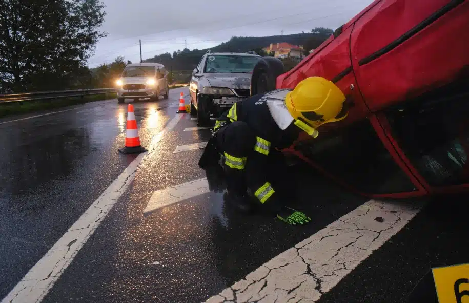 Emergency responder examining an overturned vehicle at a crash scene on a wet roadway during an accident investigation.