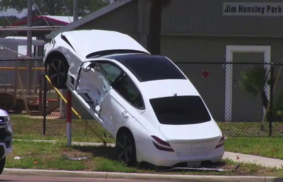 Severely damaged vehicle resting against a fence after a police pursuit ended in a crash and suspects fled on foot.