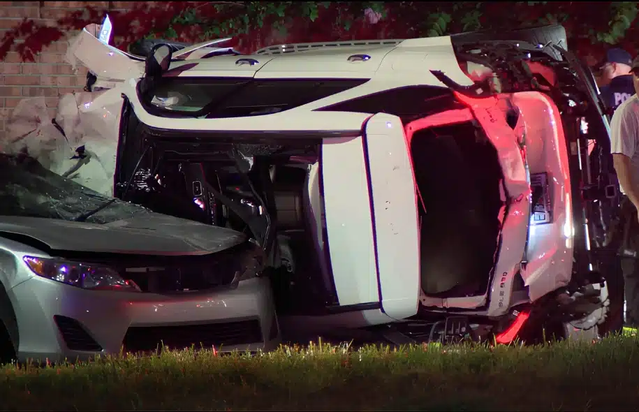 Overturned white SUV lies on its side after a nighttime crash in Ocoee, with a damaged sedan pinned beside it and emergency responders nearby.