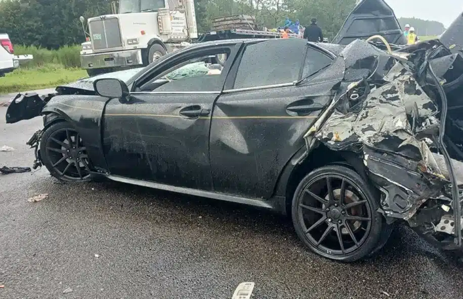 Severely damaged black sedan at the scene of a crash involving tractor-trailers on Interstate 4 near Lakeland.