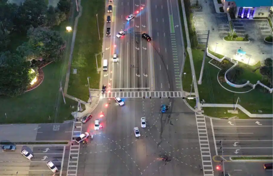 Aerial view of a multi-vehicle crash scene at a major Port St. Lucie intersection, with police vehicles and debris across the roadway.