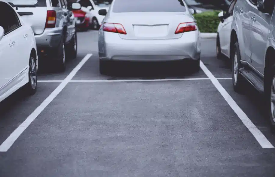 Vehicles parked in a commercial parking lot, illustrating potential risks of pedestrian accidents and injuries around moving cars.