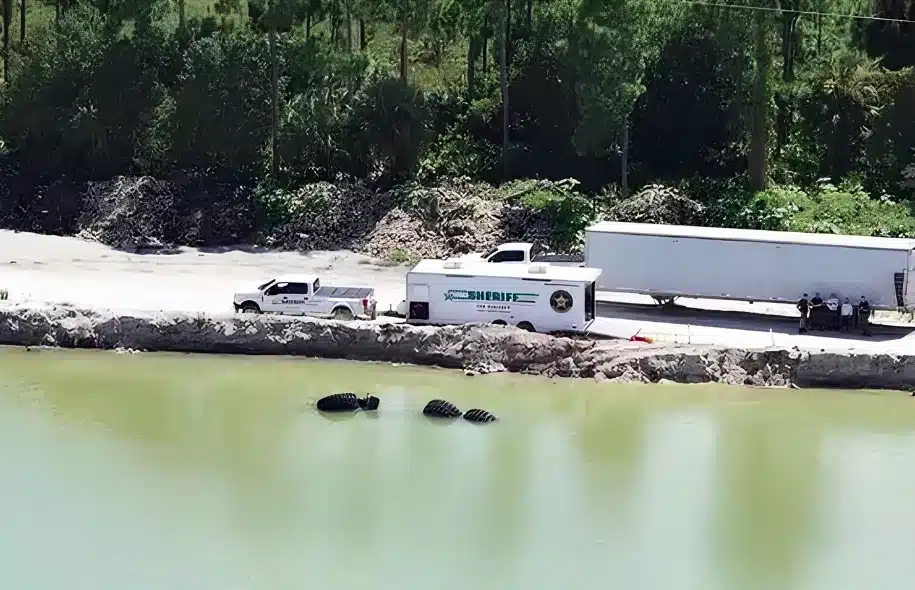 Lee County Sheriff’s Office vehicles beside a mine pond where a construction vehicle overturned into the water.