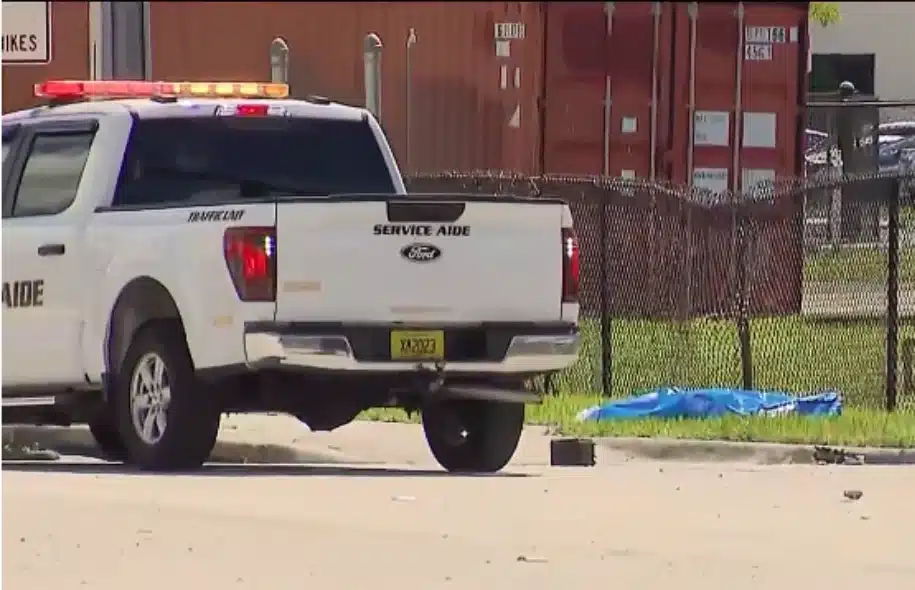 Davie service aide pickup truck parked near a crash scene with a blue tarp visible beside a fence.