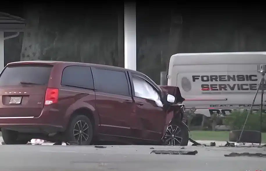 Damaged red minivan at the scene of a fatal Ocala crash, with a forensic services vehicle parked nearby.